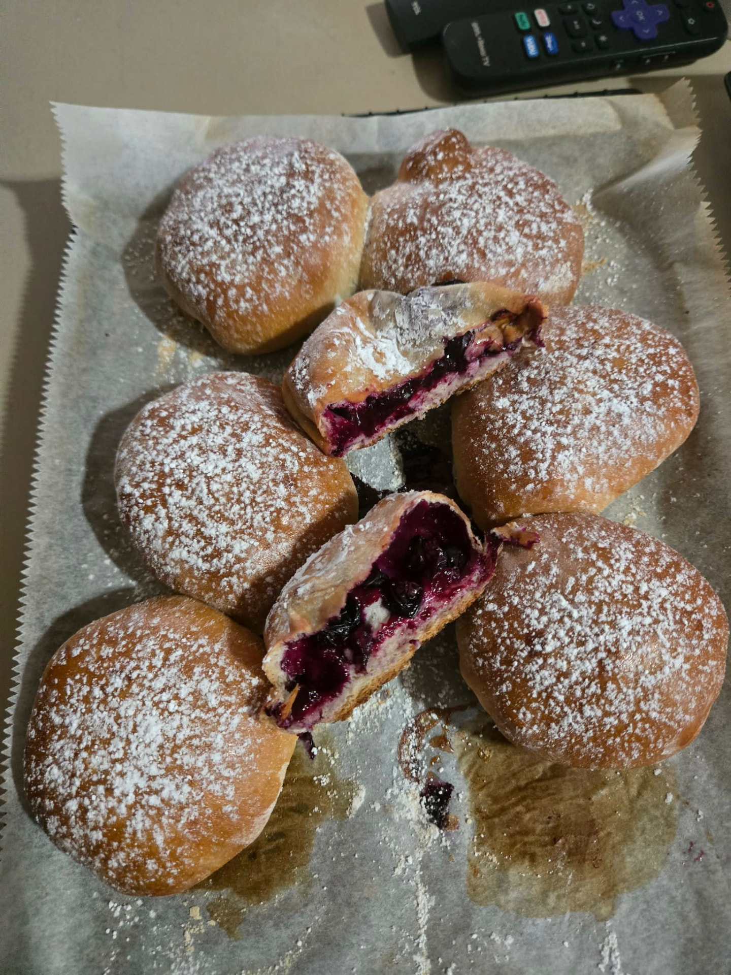 Powdered sugar doughnuts filled with blueberry, two cut open