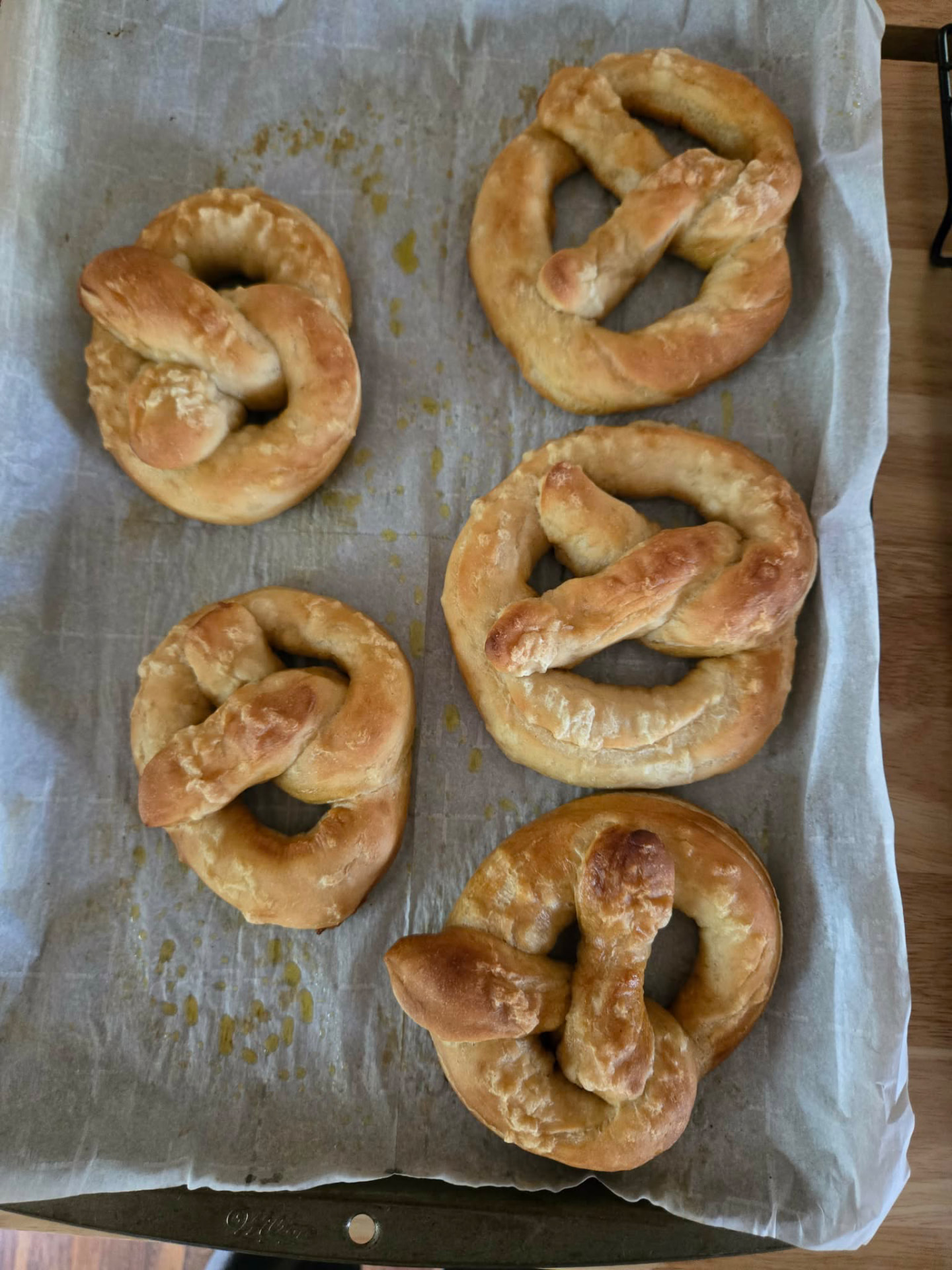 Five hand-twisted soft pretzels on parchment paper
