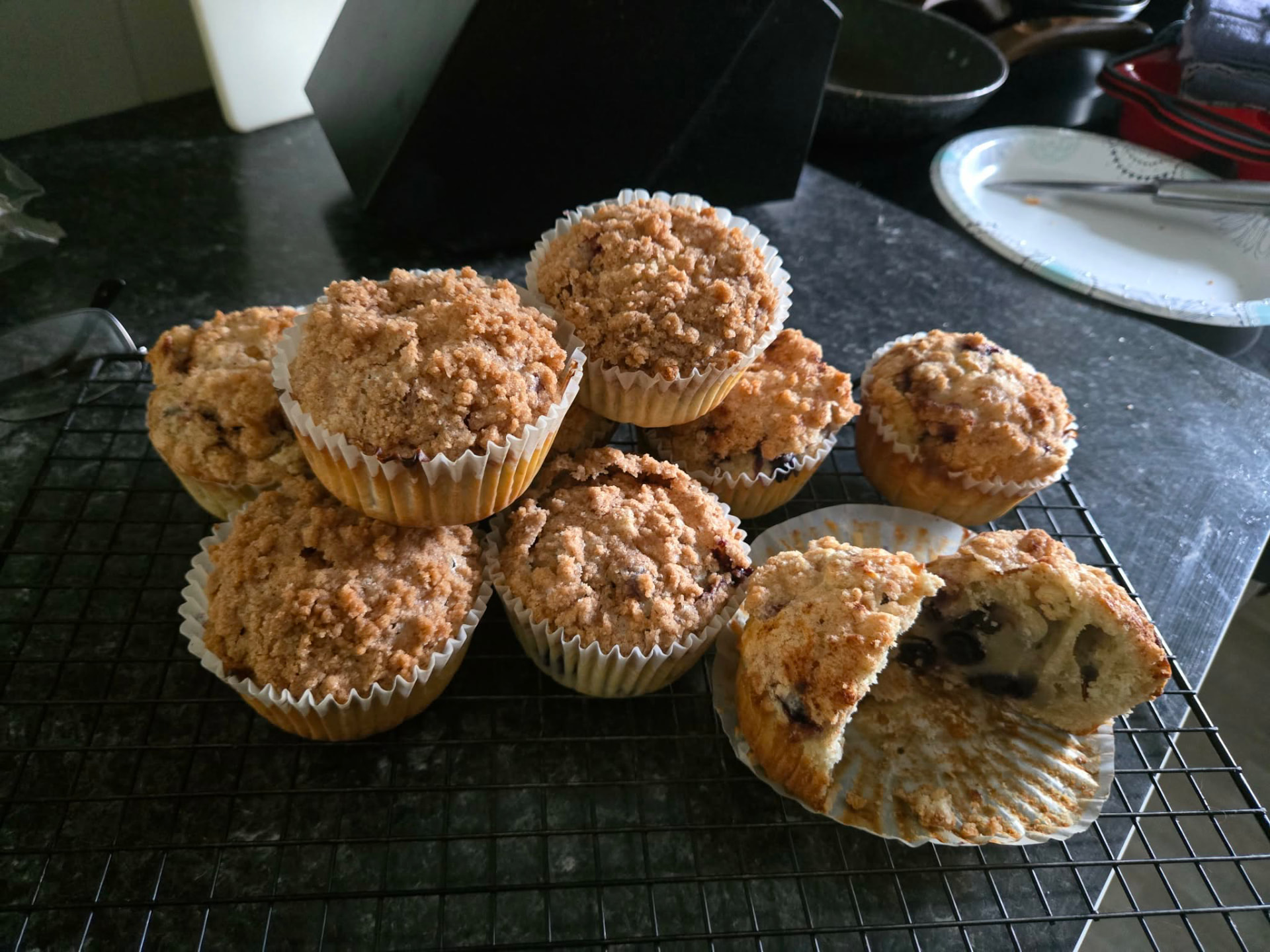 Blueberry crumb muffins on a cooling rack, one split open