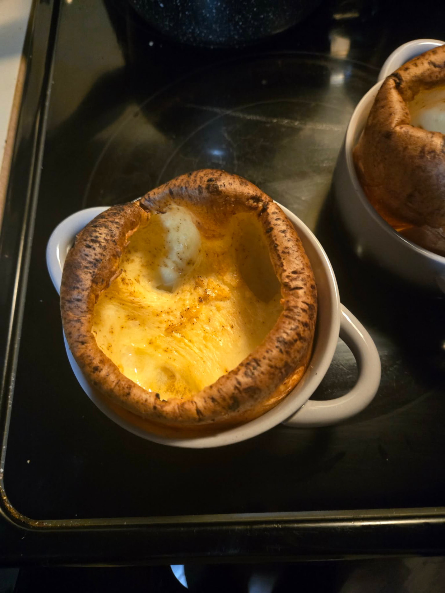 Individual Yorkshire pudding baked golden in a white crock